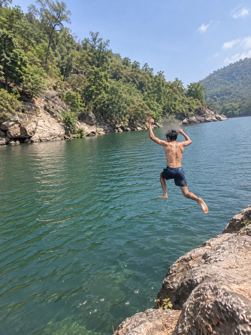 Young Indian man jumping into a lake