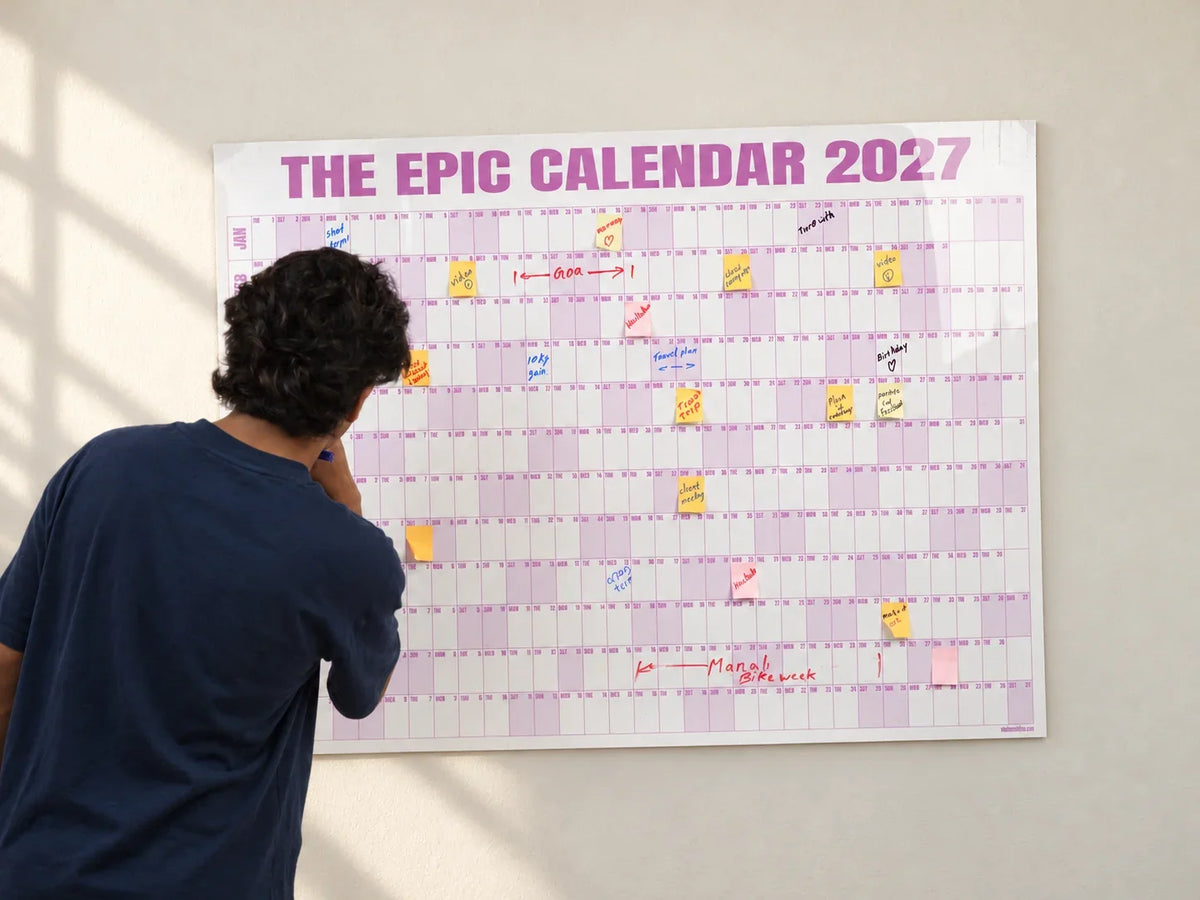 Writing plans on a Rose EPIC Calendar mounted on a softly lit wall