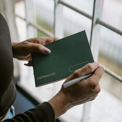 Person holding a green Dietmaster notebook