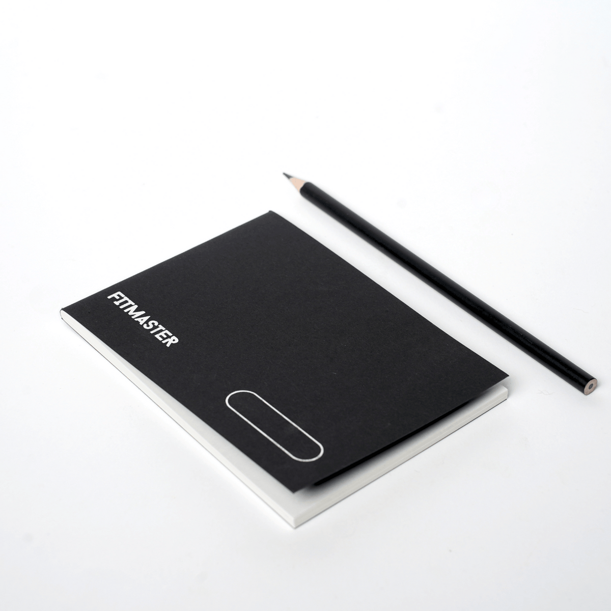 Closed Fitmaster notebook beside a pencil