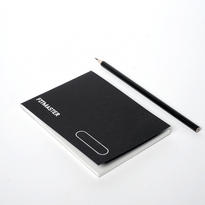Closed Fitmaster notebook beside a pencil