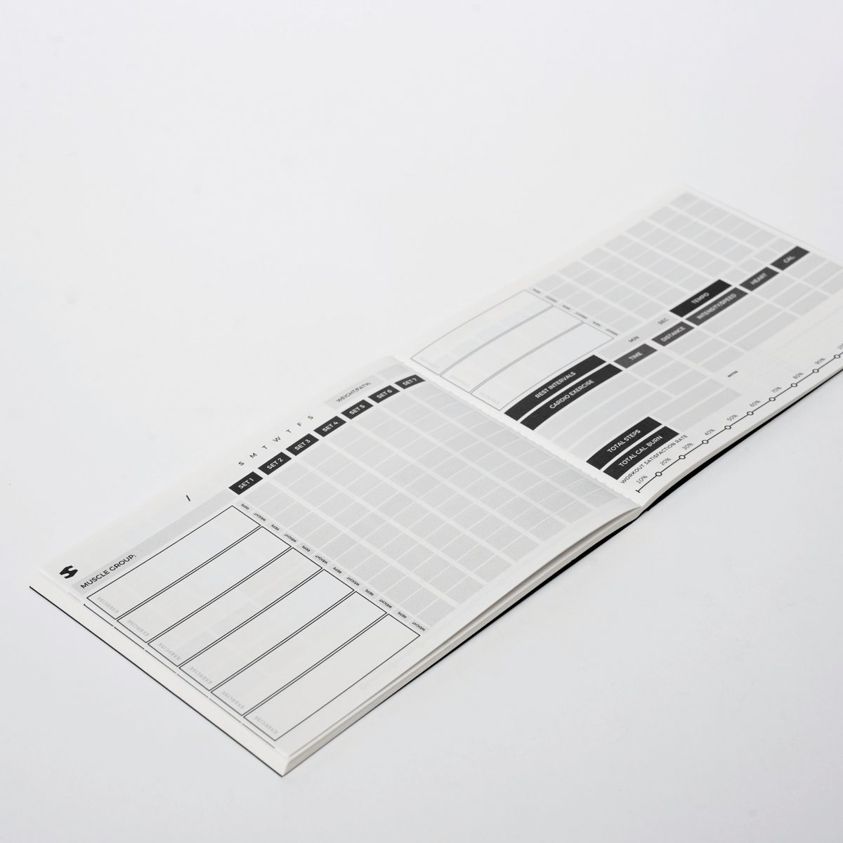 Fitmaster notebook opened to a workout and measurements spread