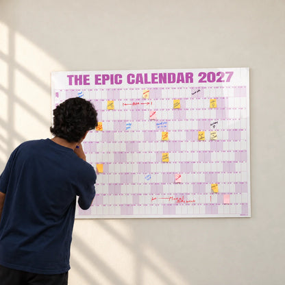 Styled photograph of a young man writing on the 48 by 36 inch Rose EPIC Calendar